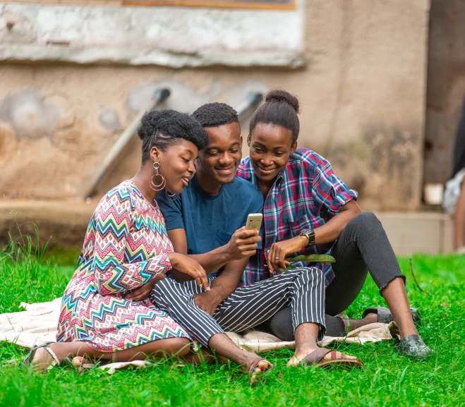 Three people sharing a mobile phone outdoors